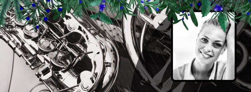 Beklager, men jeg vet ikke hvem personen i bildet er. Her er et forslag til alt-tekst: Saxofon med svart-hvitt bilde av smilende kvinne, pyntet med grønne blader og blå bær.
