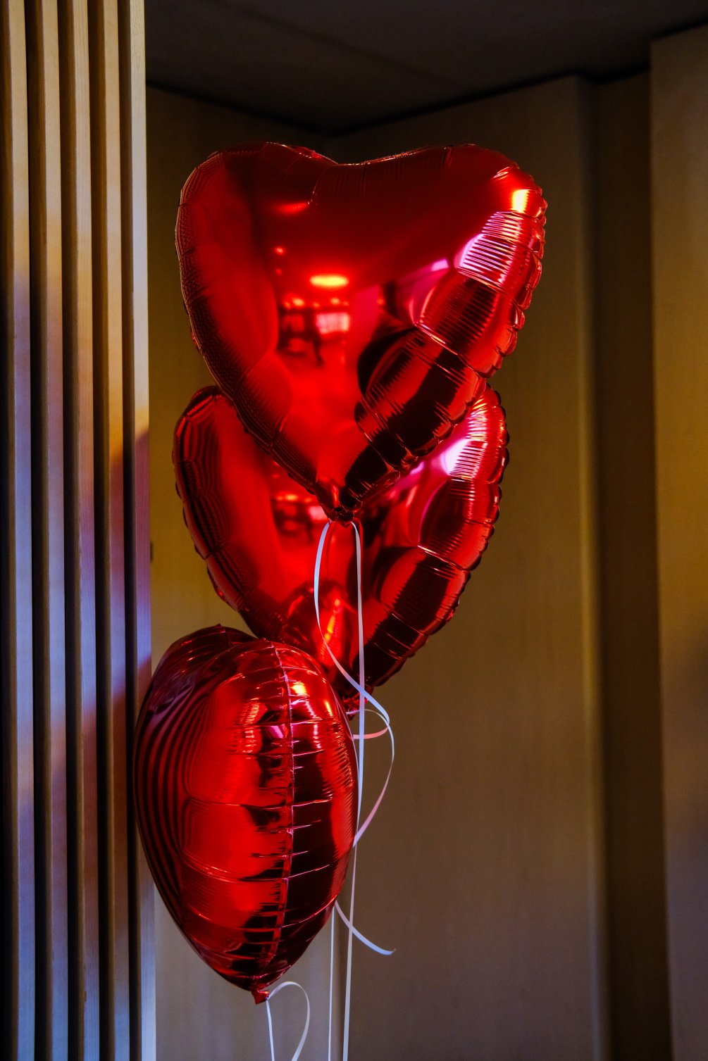 Røde hjerteformede ballonger festet til en trevegg, perfekt for romantiske anledninger og feiringer.