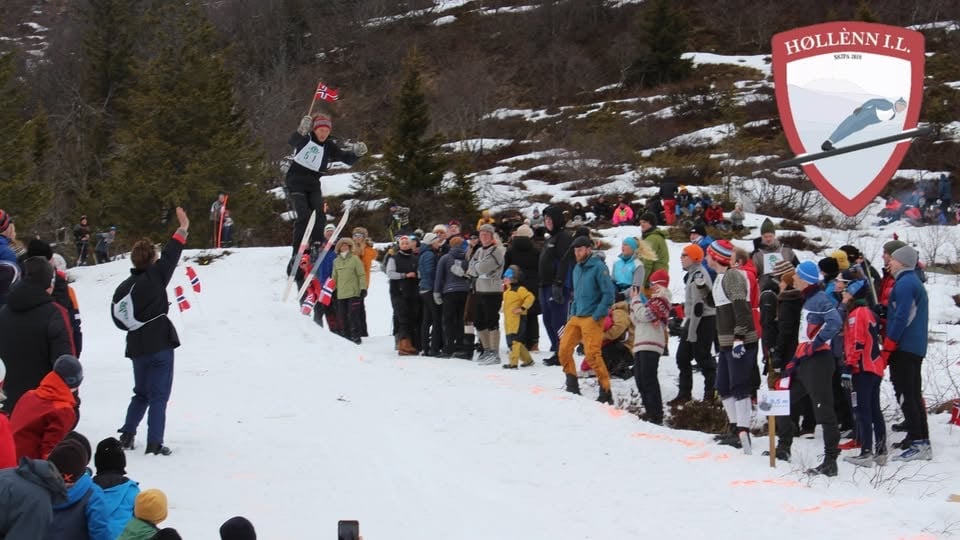 Skirenn med hoppparti, tilskuere langs sidelinjen i vinterlandskap. Hollønn IL-logo i hjørnet.