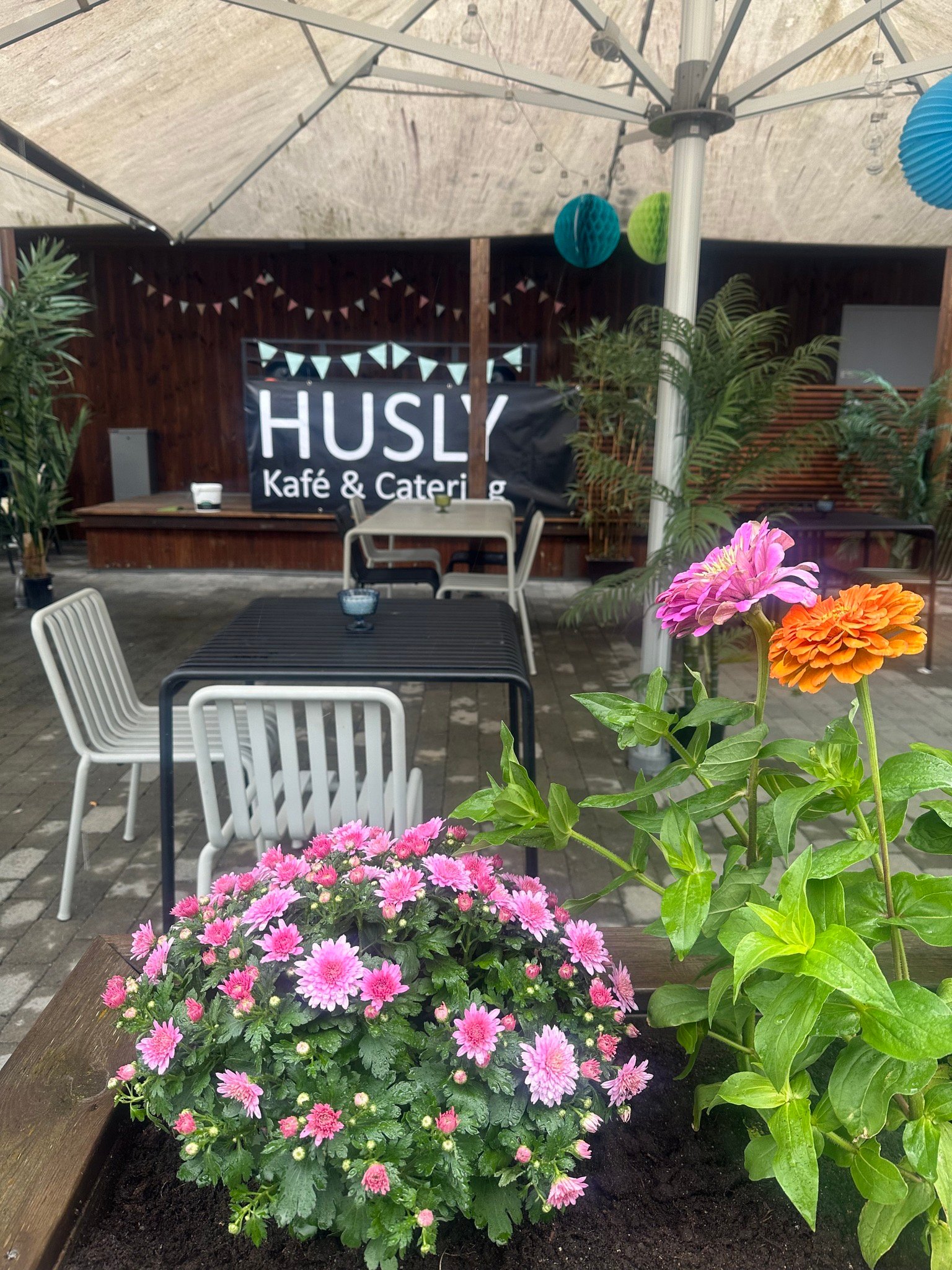 Koselig uterom på Husly Kafé & Catering med blomster og fargerike dekorasjoner.