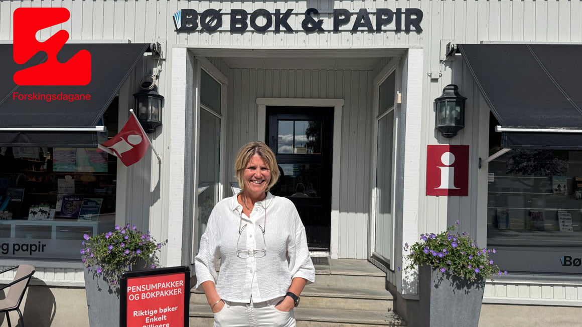 Kvinne står foran bokhandel Bø Bok & Papir med blomster og skilt om pensumpakker i finvær.
